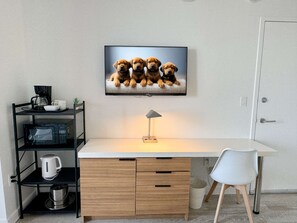A modern office space with a desk, chair, and a wall-mounted television displaying puppies. - Resort Condo 2BR Marina & City Views (Hallandale Beach)