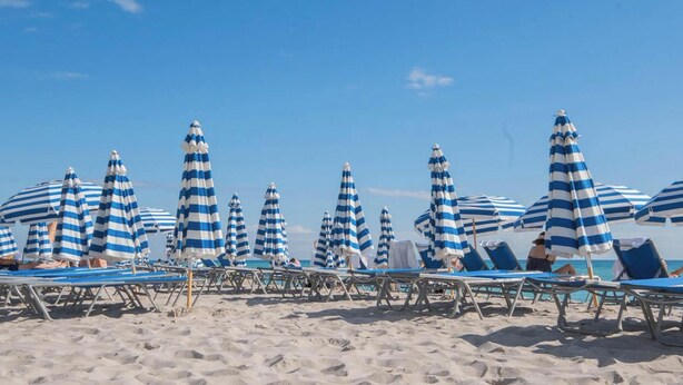 Una spiaggia con ombrelloni a righe e lettini.