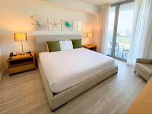 A hotel room with a large bed, two bedside tables with lamps, a chair, and artwork on the wall. - Resort Condo 2BR Marina & City Views (Hallandale Beach)