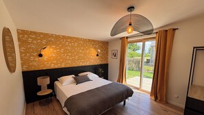 Ein Schlafzimmer mit einem Bett, einem Nachttisch, einer Lampe, einer Wandleuchte, einem Deckenventilator und einer Glastür, die zu einem Außenbereich führt.