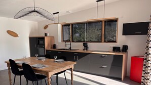 Eine moderne Küche mit einem Holztisch, schwarzen Stühlen und einem roten Schrank.