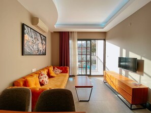 Una sala de estar moderna con sofá, mesa de centro, televisor y vistas al balcón.