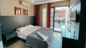 Ett hotellrum med en säng, ett nattduksbord, en TV och en balkong med utsikt över poolen.
