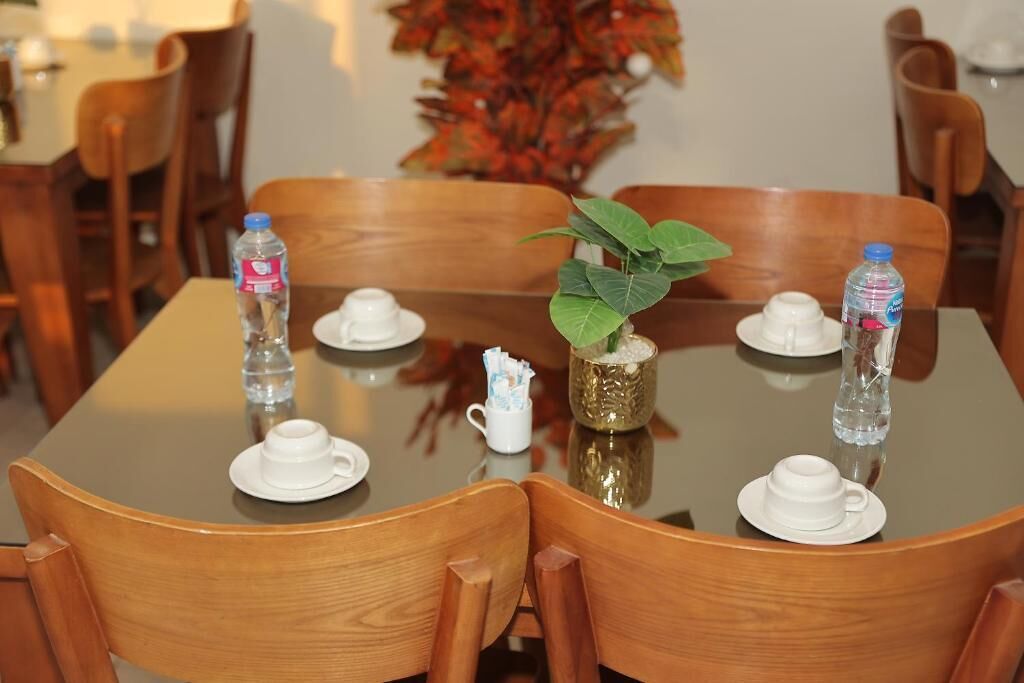 A dining table with chairs, water bottles, and a small plant.