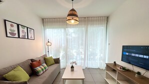 A living room with a sofa, a coffee table, a TV, and a pendant light. - STAY Tropical Apartment (Protaras)