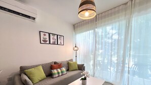 A living room with a sofa, a coffee table, and a hanging light fixture. - STAY Tropical Apartment (Protaras)