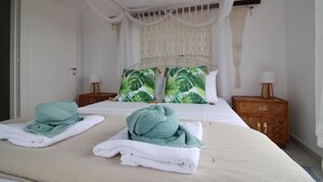 Une chambre d’hôtel avec un lit, deux tables de chevet, une commode en bois et un lit à baldaquin.