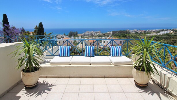 Une terrasse avec vue sur la mer, une balustrade et des plantes en pot.