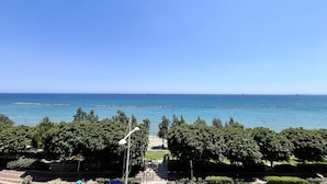 Vista costera con cielo despejado, árboles y un barco a lo lejos.
