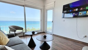 Una sala moderna con un televisor grande, asientos cómodos y vistas al océano.