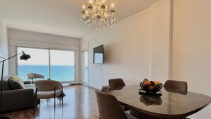 Una habitación amplia con una mesa de comedor, sillas, una araña, un sofá y un televisor.