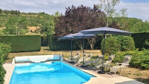 A swimming pool with lounge chairs and a table, surrounded by hedges and trees. - House with a pool; 4 bedrooms, including 2 with double beds (Chassey-le-Camp)