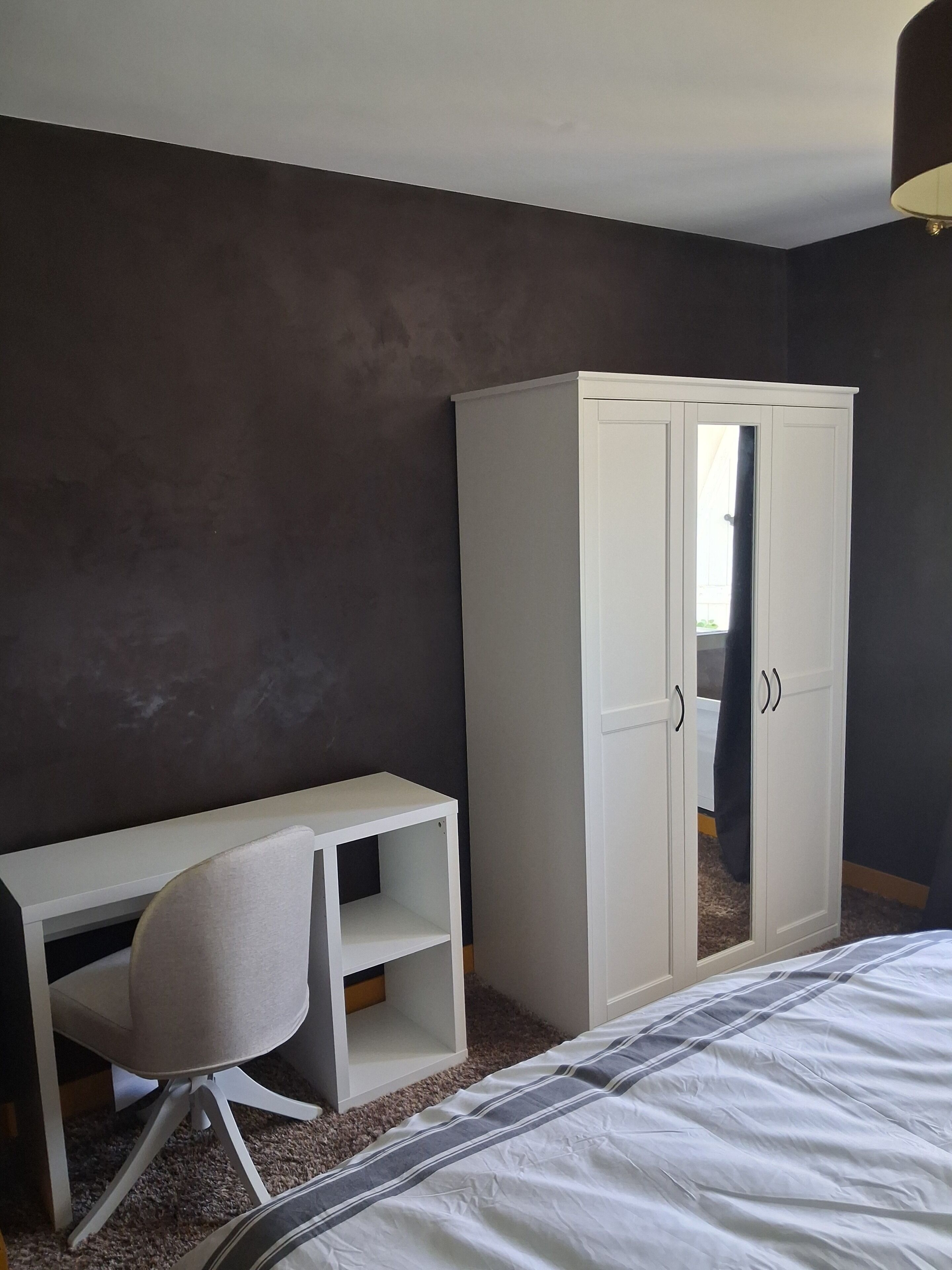 Un dormitorio con cama, escritorio con silla y armario.