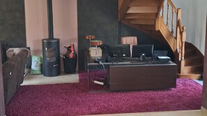 A living room with a fireplace, a sofa, a coffee table, and a wooden staircase. - House with a pool; 4 bedrooms, including 2 with double beds (Chassey-le-Camp)