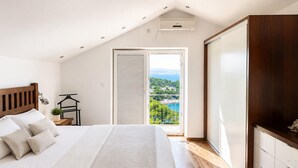 Una camera da letto con un letto, un comodino, una lampada a sospensione, un armadio e un balcone con vista.