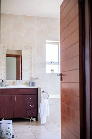 A bathroom with a wooden vanity, a large mirror, a window, and a towel hanging on the wall. - Room-luxurious Mansion - Lower (Johannesburg)