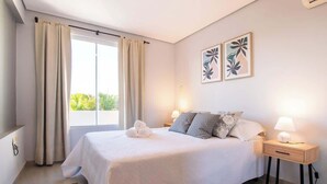 A bedroom with a bed, two bedside lamps, a nightstand, a window with curtains, and two wall art pieces. - Corporate Stays Terraza flats (Asunción)