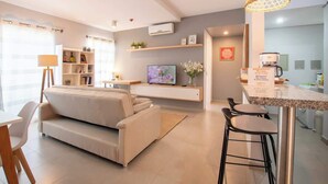 A modern living room with a sofa, TV, and bar area. - Corporate Stays Terraza flats (Asunción)