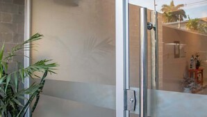A glass door with a metal handle, a potted plant, and a reflection of a room with a tiled floor and a small table with a vase. - Corporate Stays Terraza flats (Asunción)