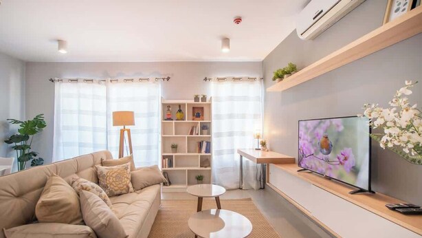 A modern living room with a sofa, a coffee table, a TV, and a bookshelf. - Corporate Stays Terraza flats (Asunción)