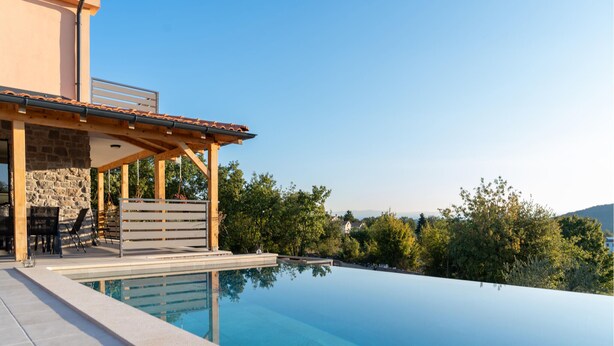 A modern outdoor pool area with a stone wall, wooden pergola, and a clear view of the surrounding greenery. - Awesome home in Motovun (Motovun)