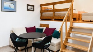 A room with a sofa, two chairs, a table, a wooden staircase, and two framed pictures on the wall. - 1 bedroom beach front apartment in Smokvica (Smokvica)