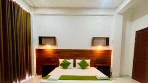Habitación de hotel con una cama grande, cabecero de madera, dos mesitas de noche y una alfombra redonda.