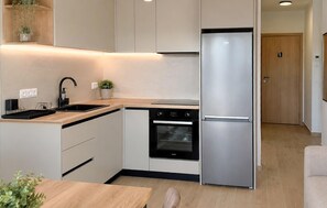 Eine moderne Küche mit Einbauofen, einem Edelstahl-Kühlschrank und einer Holz Arbeitsplatte.