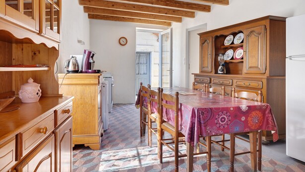 A kitchen with wooden cabinets, a dining table with chairs, and a refrigerator. - Country House “La Demeure D'Elles” with Private Terrace and Garden (Le Thou)