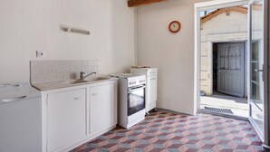 A compact kitchen with white cabinets, a built-in oven, and a window. - Country House “La Demeure D'Elles” with Private Terrace and Garden (Le Thou)