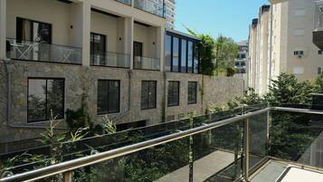 A modern apartment building with balconies, large windows, and a stone facade.