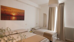 Ein Hotelzimmer mit zwei Betten, einem großen Gemälde, einem Fenster mit Vorhängen und einer Heizung.