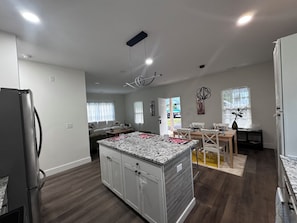 A modern kitchen with a central island, wooden flooring, and a dining area with a table and chairs. - Hermosa casa Nueva de 3 habitaciones y 2 Banos, parqueadero 2 autos (Salisbury)