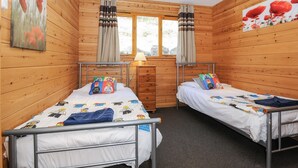 A wooden cabin room with two beds, a window, and a lamp. - Trevano (Bodmin)