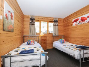 A wooden cabin room with two beds, a window, and a lamp. - Trevano (Bodmin)