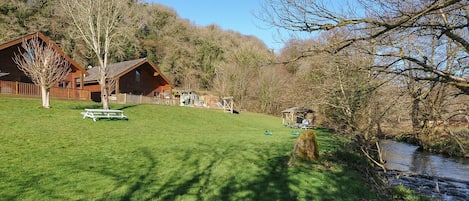 A rustic lodge with a picnic table and a playground in a wooded area.