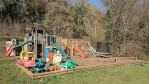 A playground with a wooden playhouse, slides, and a train ride. - Trevano (Bodmin)