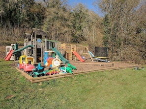 A playground with a wooden playhouse, slides, and a train ride. - Trevano (Bodmin)