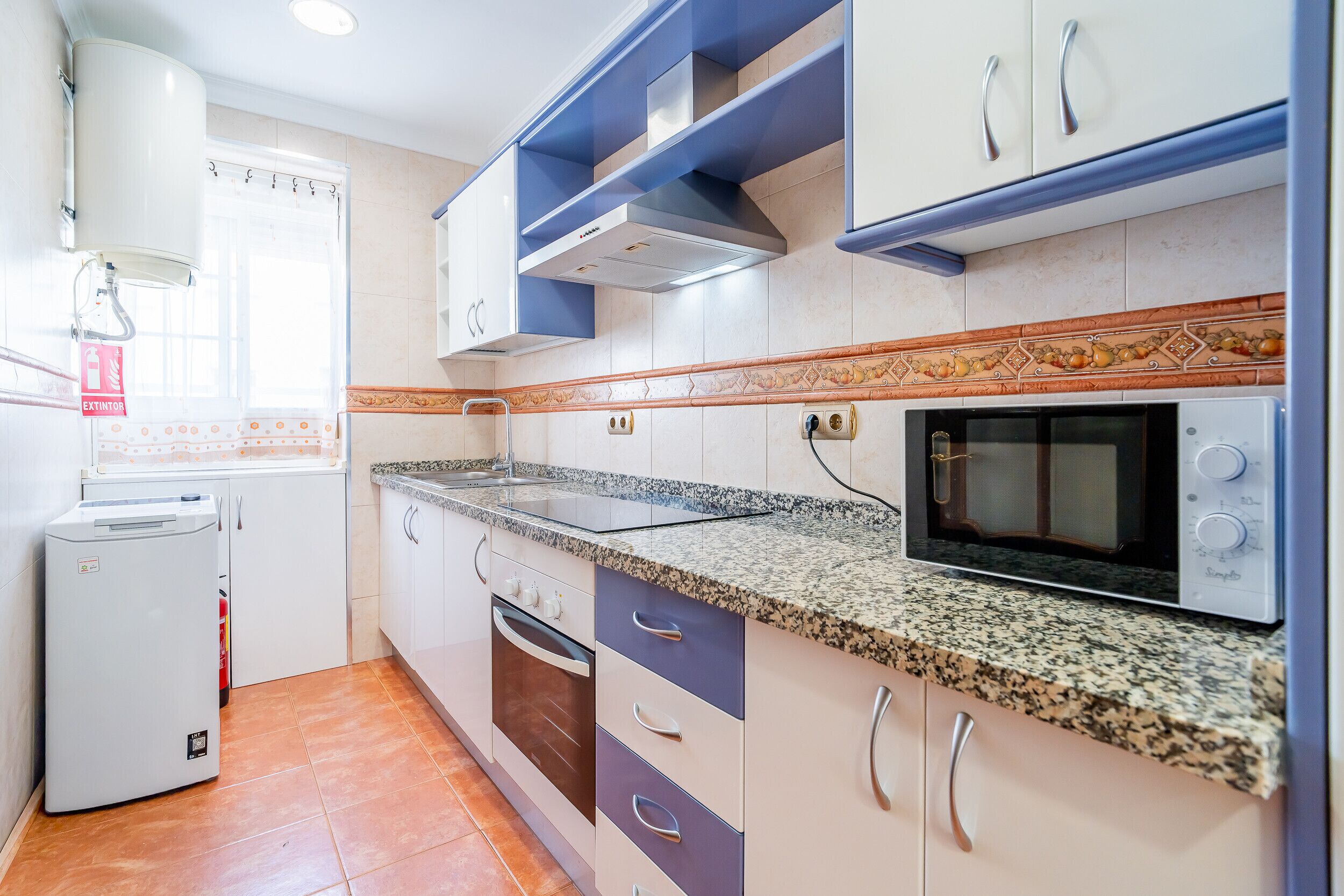 A kitchen with white cabinets, a granite countertop, a built-in oven, and a microwave.