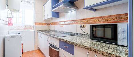 A kitchen with white cabinets, a granite countertop, a built-in oven, and a microwave.