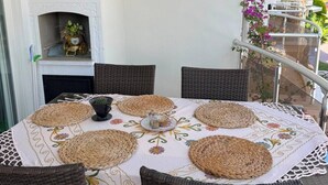 A round table with woven placemats, wicker chairs, and a white tablecloth with floral patterns. - Beautiful 2-bedroom condo with AC in enchanting in Sunset Beach Club,Fethiye (Muğla)