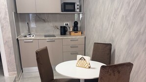 A modern kitchen with a microwave, kettle, and coffee maker on the countertop. There is a round dining table with four chairs.