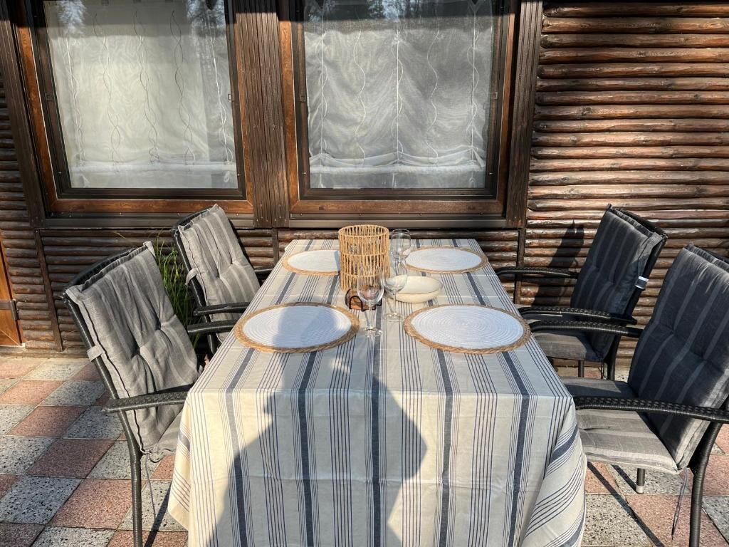 A round dining table with striped tablecloth, six chairs, and a woven centerpiece.