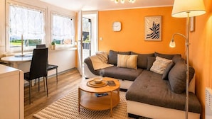 Un salon chaleureux avec un canapé, une table basse, une lampe et une vue par la fenêtre.