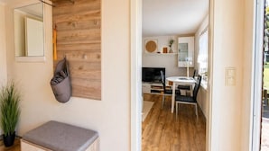 Un intérieur moderne comprenant un banc, un miroir, un mur en bois, un coin repas avec une table et des chaises, et un téléviseur.