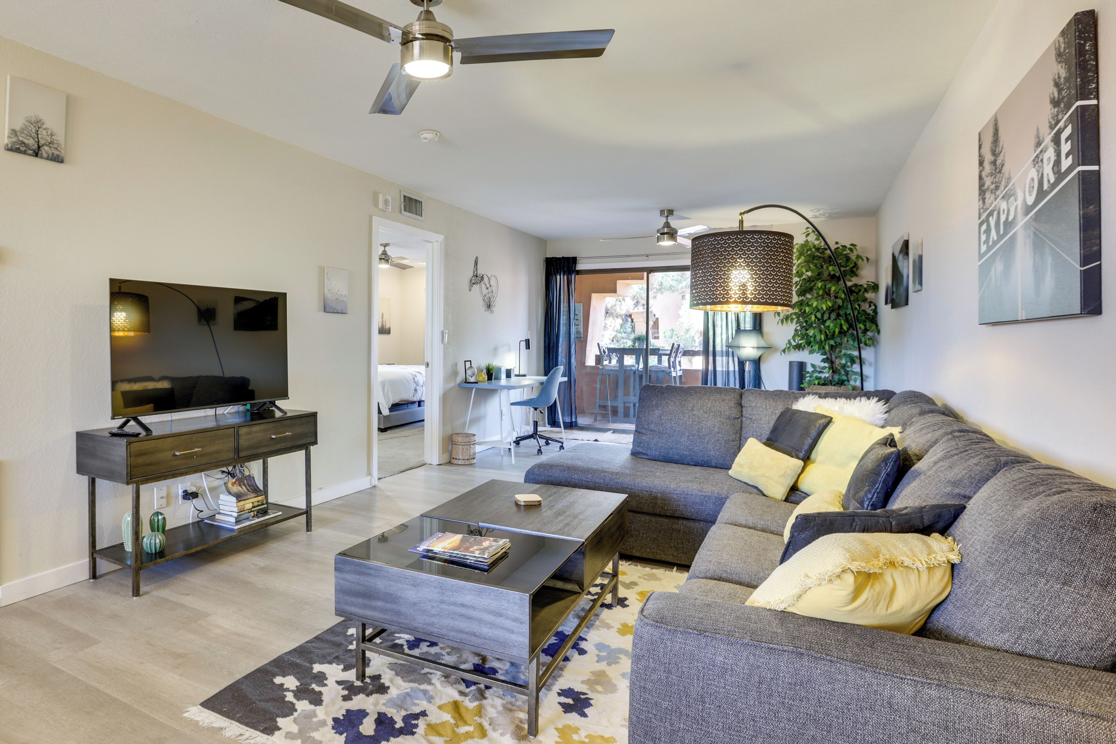 Ein modernes Wohnzimmer mit Sofa, Couchtisch, Fernseher und Deckenventilator.