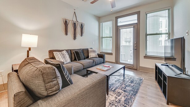 A living room with a sofa, coffee table, and TV stand. - Pet-friendly Condo w/ Community Perks in Dallas! (Dallas)