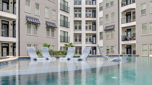 A swimming pool with lounge chairs and a building with multiple balconies in the background. - Pet-friendly Condo w/ Community Perks in Dallas! (Dallas)