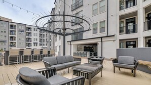 An outdoor seating area with modern furniture, a central light fixture, and a view of a multi-story building. - Pet-friendly Condo w/ Community Perks in Dallas! (Dallas)