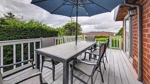 Una terraza con una mesa y sillas, un paraguas azul y un muro de ladrillo.